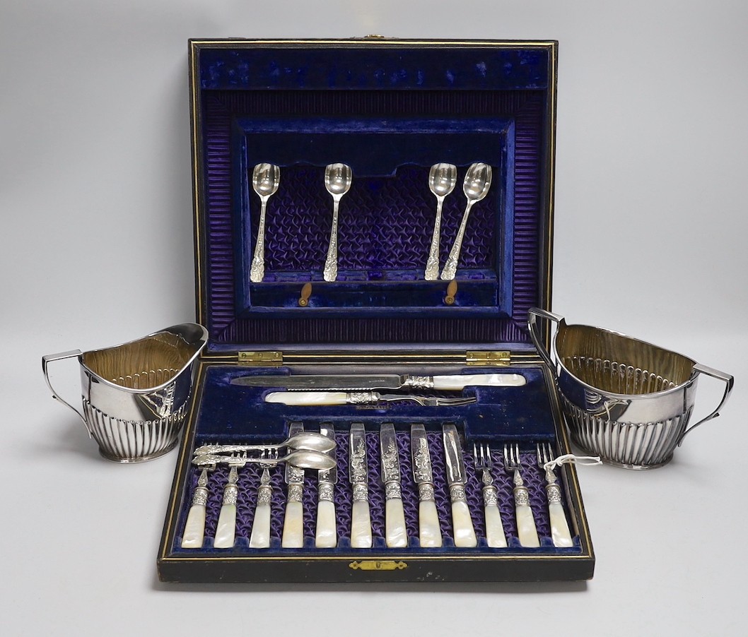 Six pairs of silver plated and engraved dessert knives and forks, with server, mother of pearl handles and six teaspoons (cased) and a silver plated cream jug and sugar bowl.